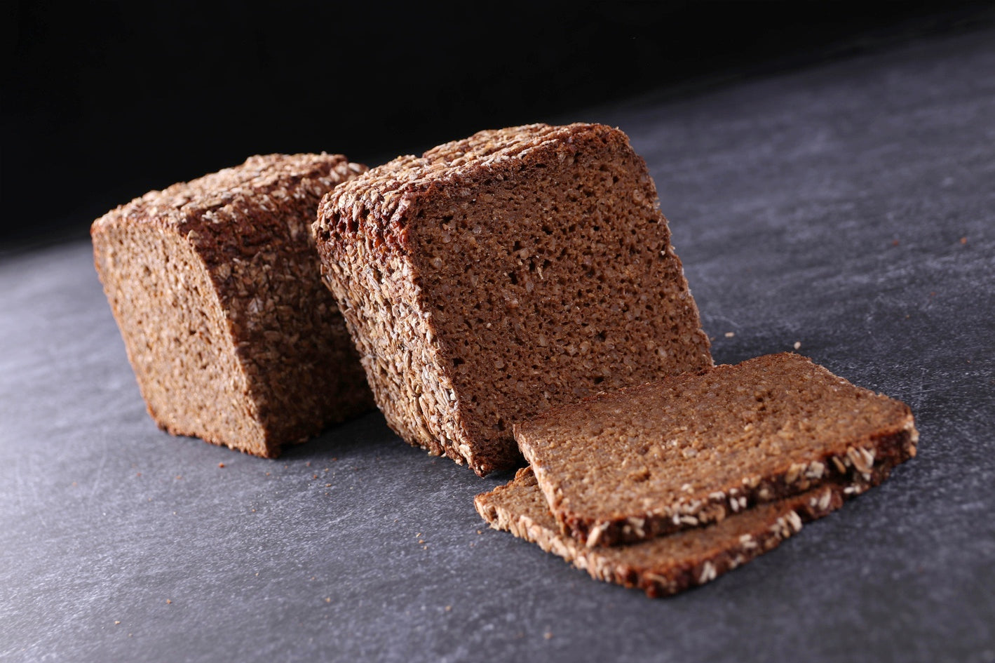 Zwei Brote neben zwei Scheiben Vollkornbrot